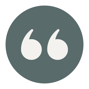 A dark gray circle with a pair of white quotation marks in the center.