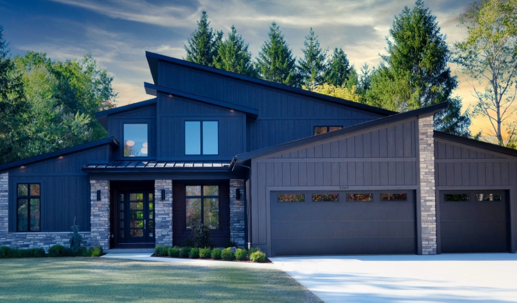 Modern house with dark exterior, large windows, and a three-car garage, expertly crafted by a custom home builder. Nestled among tall trees in the serene surroundings of Eagle River, WI.