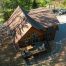 Aerial view of a wooden cabin with a deck and outdoor seating, surrounded by trees and gravel in a forest clearing, built on an ICF Foundation for added durability and energy efficiency.