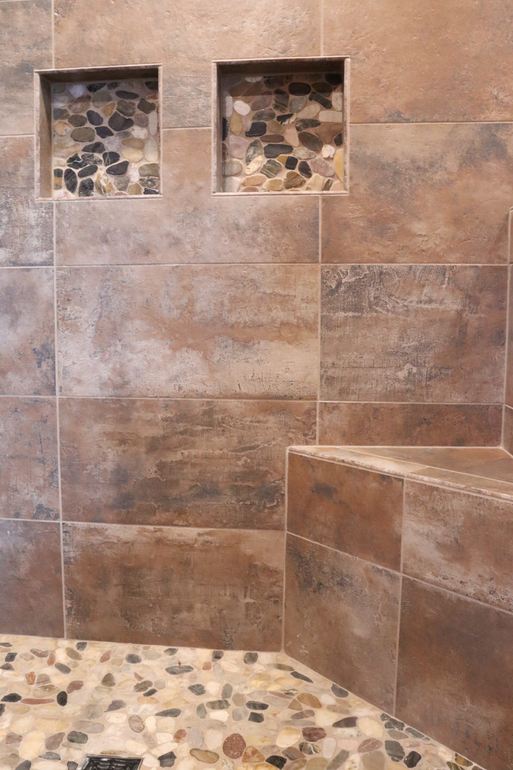 A shower with a bench features a stylish tile pattern and a sleek stone bench, perfect for your new home.