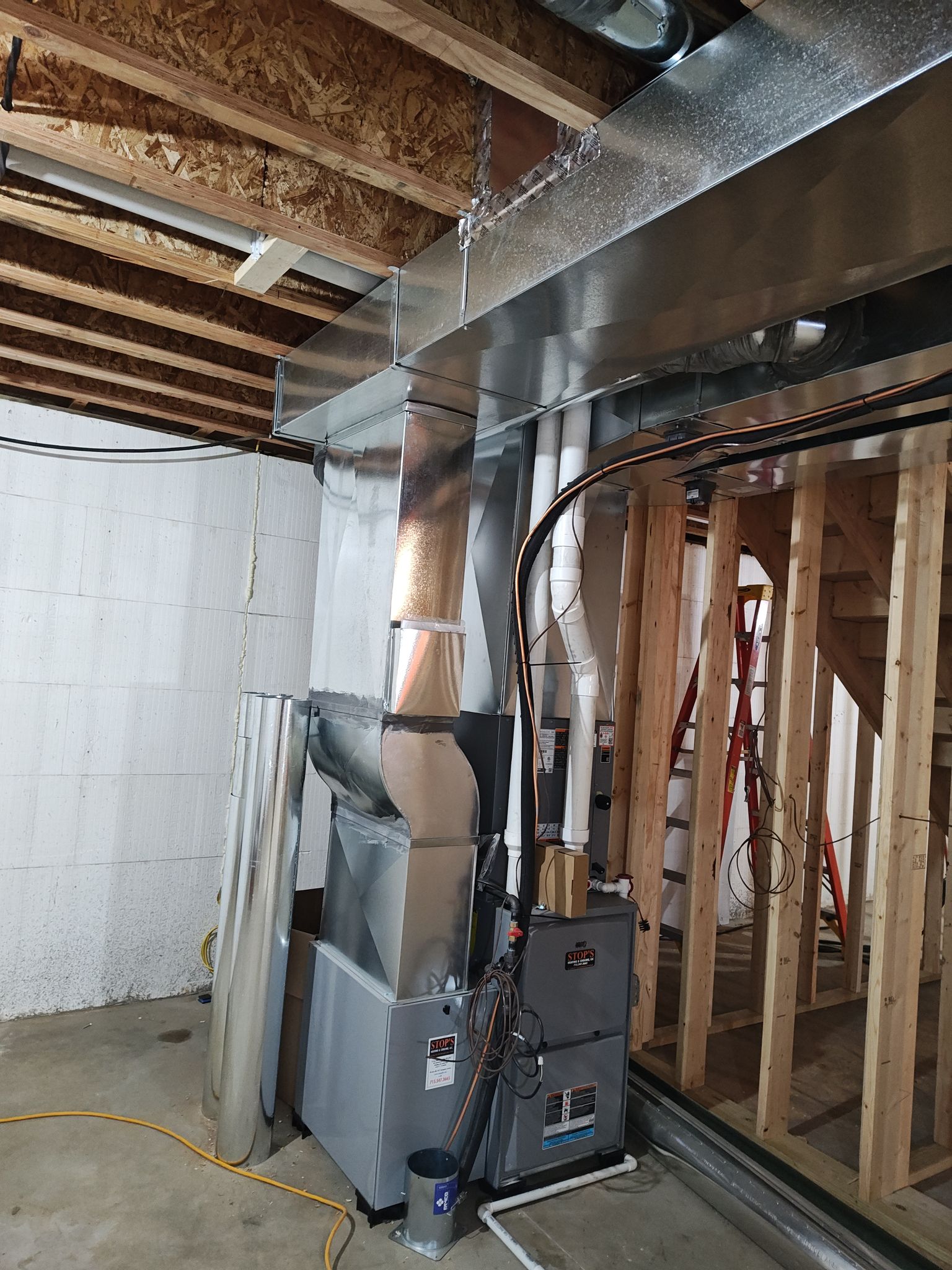 A modern HVAC furnace and ductwork system installed in an unfinished basement with exposed wooden framing and ceiling beams, ready to complement upgrades like custom tile showers.